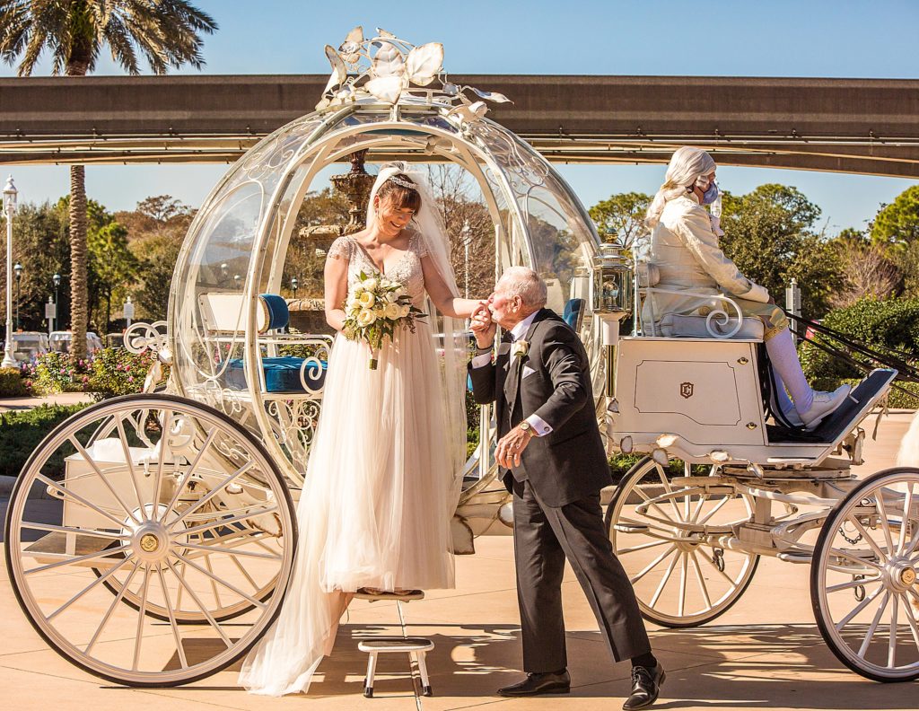 grandfather kissing brides hand as she exits Cinderellas Carriage at Disney Wedding Pavillion