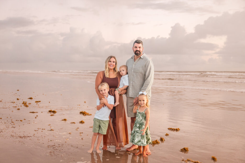Family of four smiling during sunset session in New Smyrna Beach 